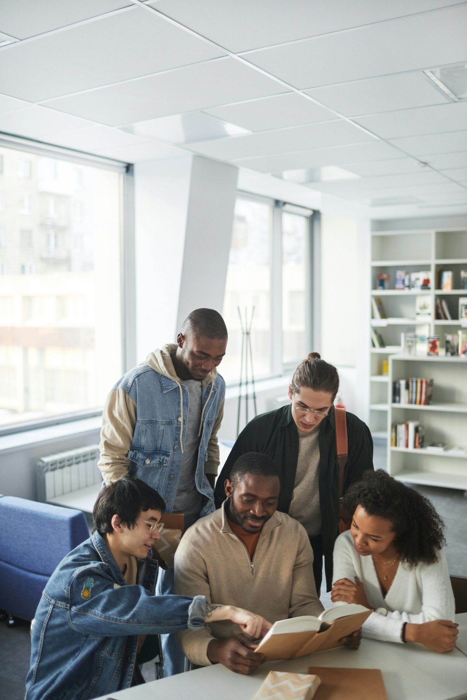 A diverse group of students collaborates in a bright, modern library setting, symbolizing teamwork and education.